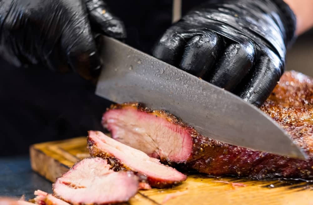 Across the grain and thinly sliced is the best way to enjoy brisket and get the most tender eating experience.